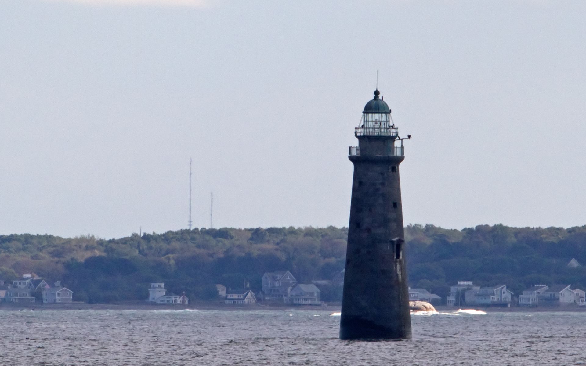 Minot's Ledge Light, the granite lighthouse standing in the sea off Cohasset and Scituate, Massachusetts, with the South Shore coastline behind it